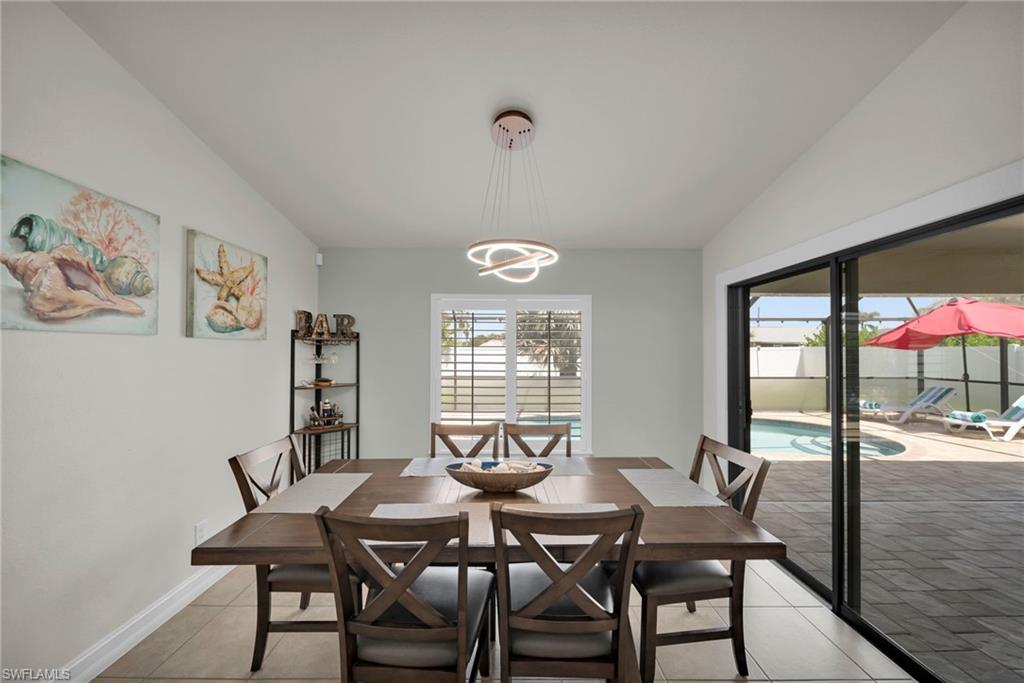 Dining area featuring light tile patterned flooring, a chandelier, and lofted ceiling