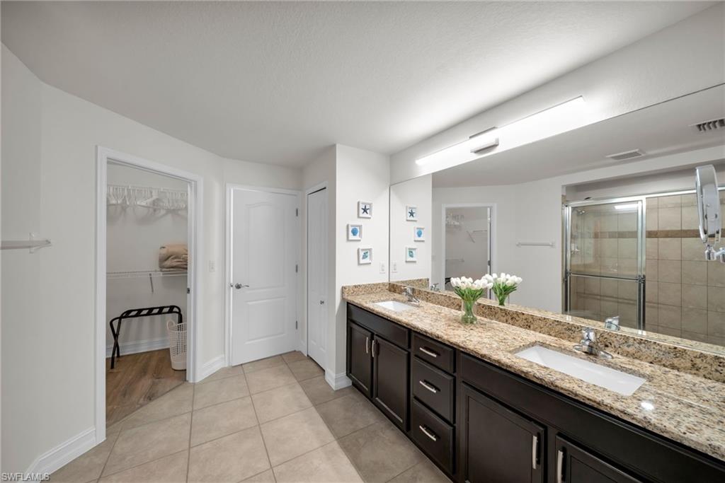 Full bath with a walk in closet, a sink, and a shower stall