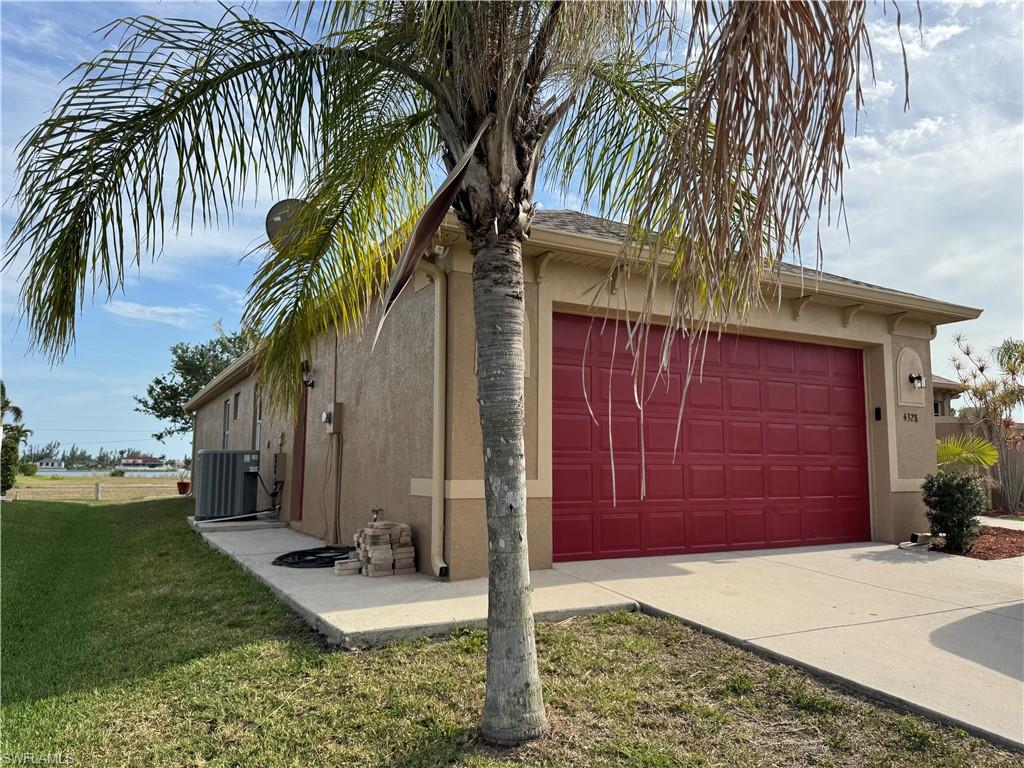 View of front of home with stucco siding, driveway, a garage, and a front yard