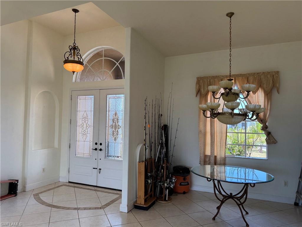 Spare room with a towering ceiling, visible vents, light tile patterned floors, baseboards, and ceiling fan