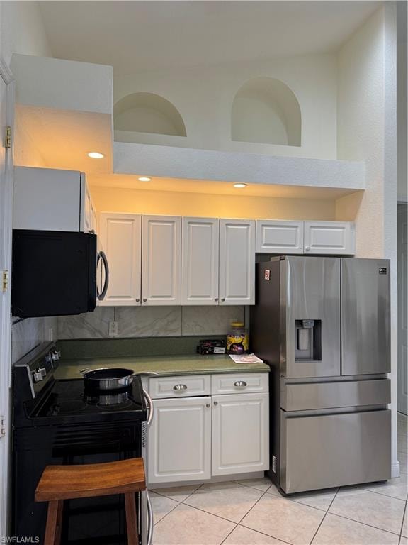 Kitchen with stainless steel dishwasher, dark countertops, a sink, white cabinets, and a peninsula