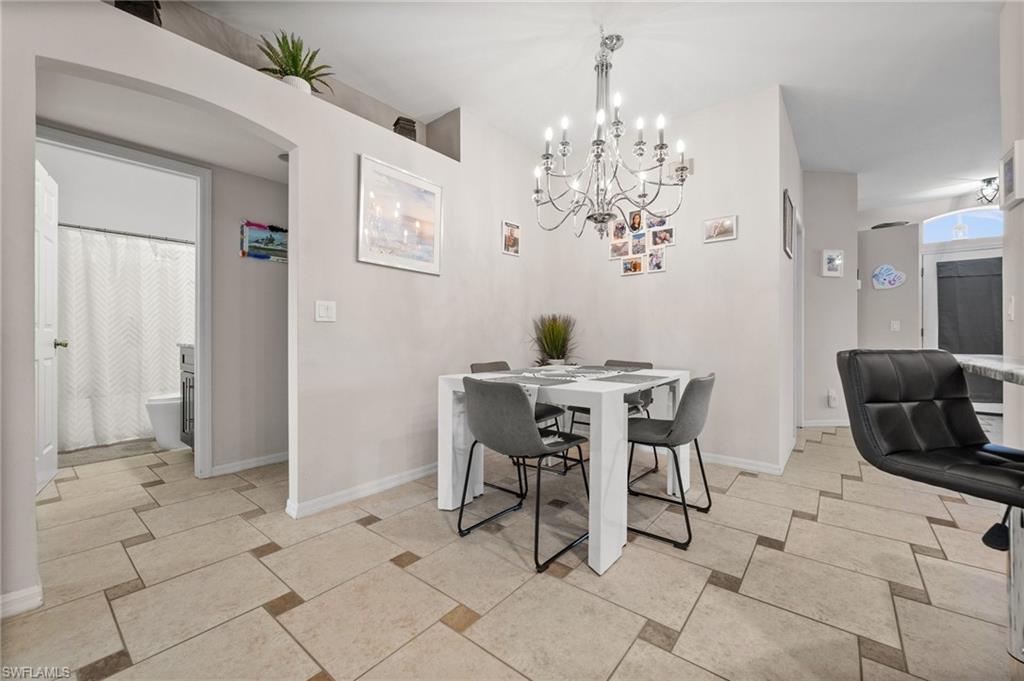Dining room with a chandelier, baseboards, and arched walkways