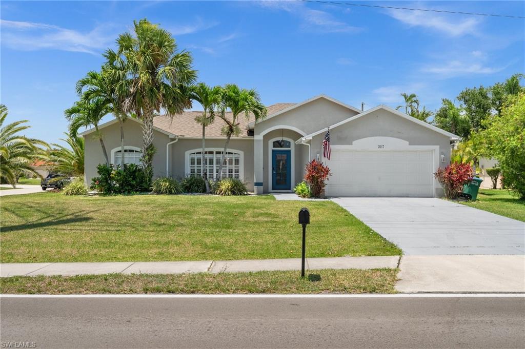 Single story home featuring a garage, stucco siding, a front yard, and driveway