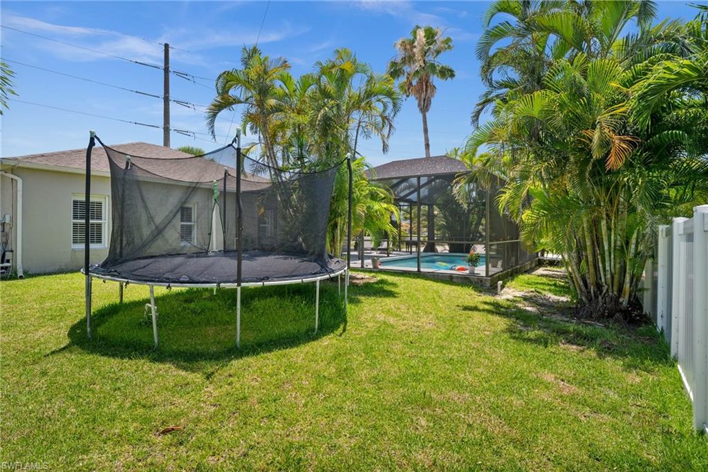 View of green lawn with a trampoline and an outdoor pool