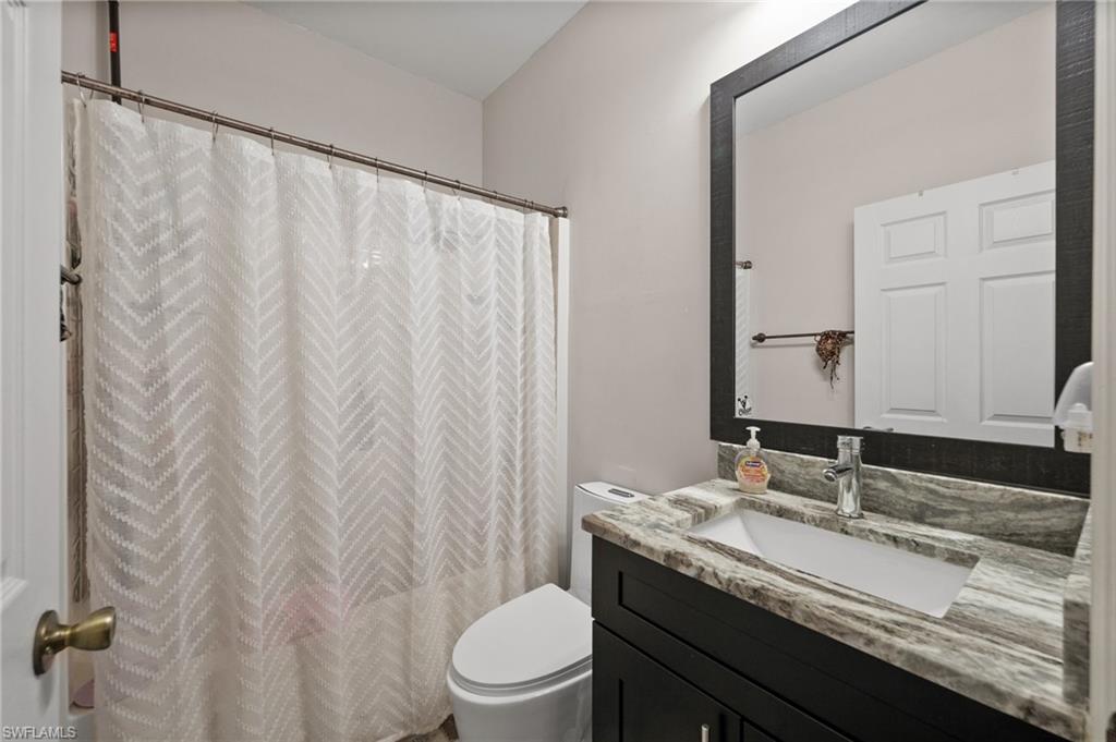 Full bath with toilet, vanity, and curtained shower