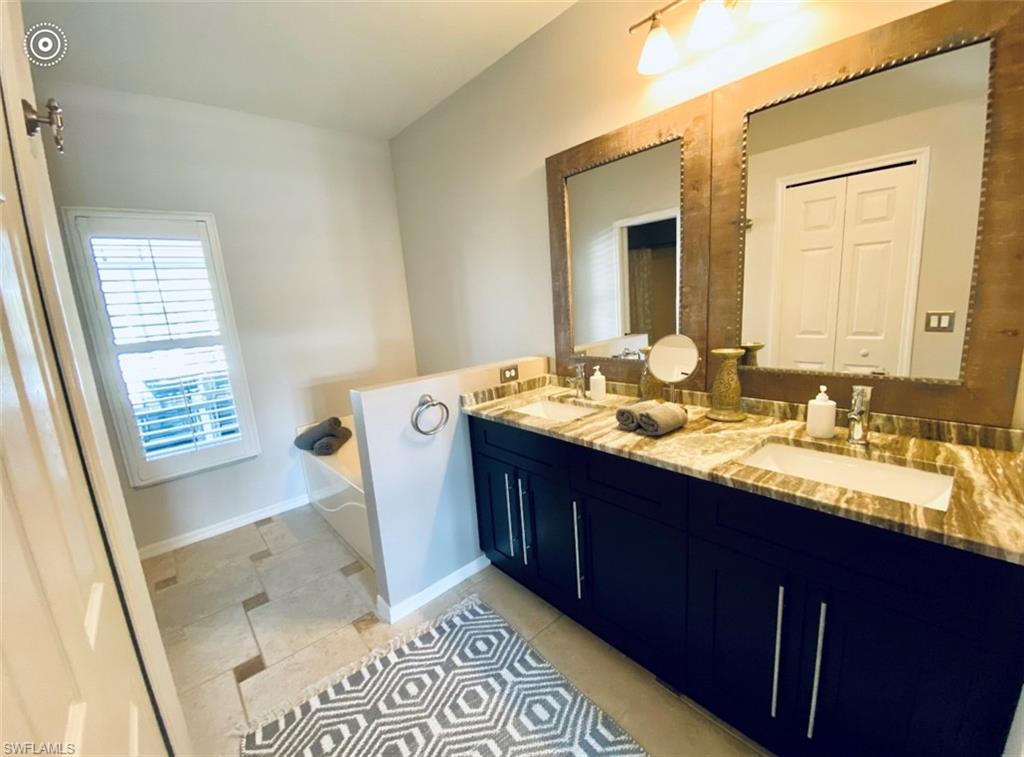 Full bathroom with double vanity, a bath, baseboards, and tile patterned floors