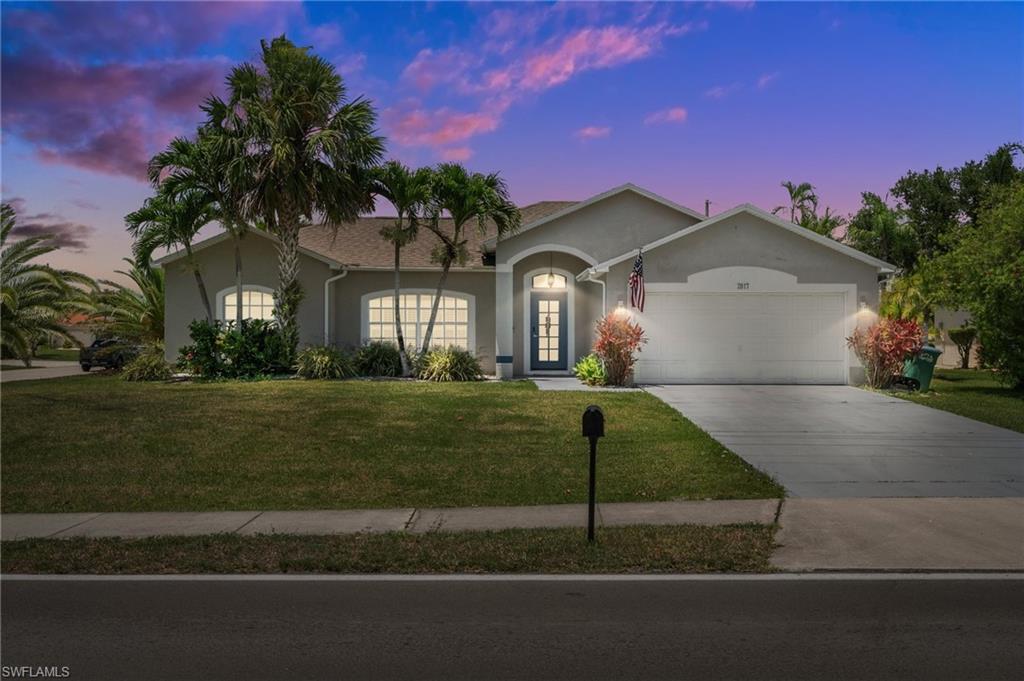 Ranch-style home with stucco siding, an attached garage, a yard, and concrete driveway