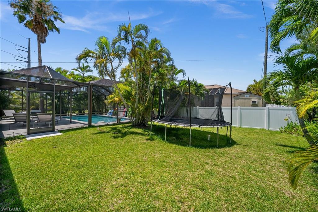 View of yard featuring a trampoline, a patio area, and a lanai