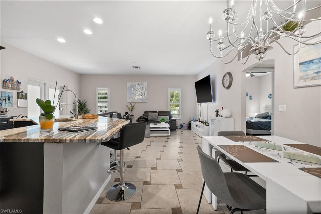 Kitchen featuring a kitchen bar, recessed lighting, open floor plan, a chandelier, and a center island with sink