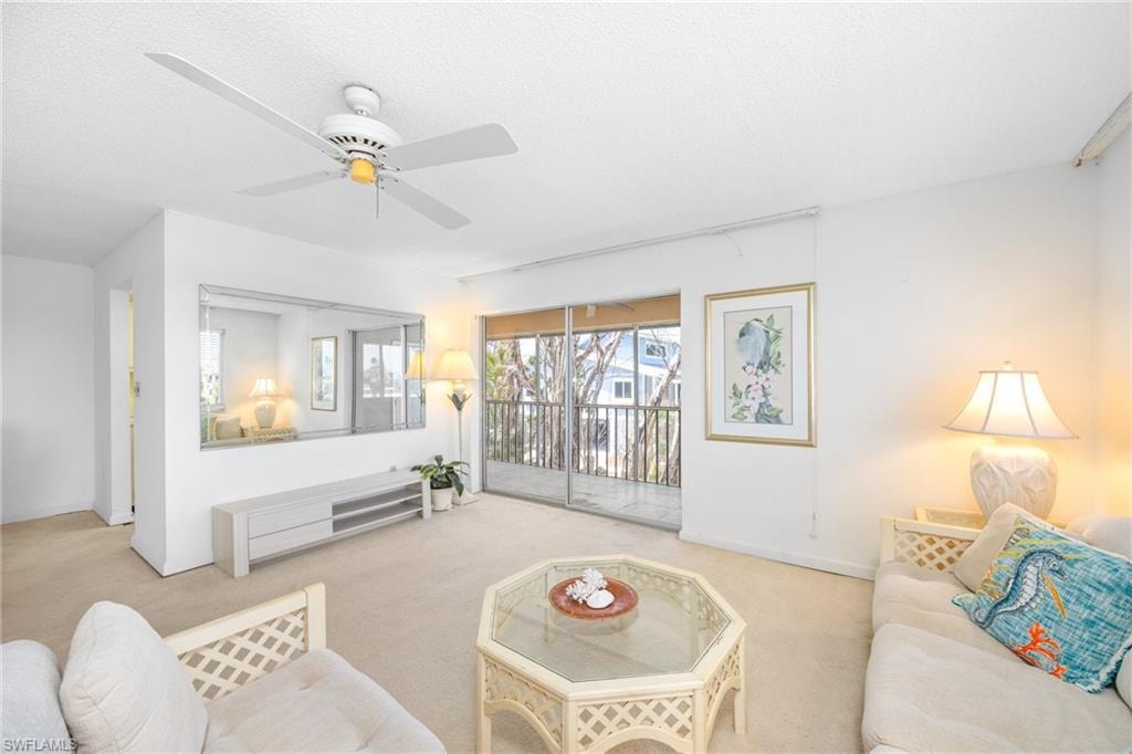 Living room with carpet floors, a ceiling fan, and baseboards