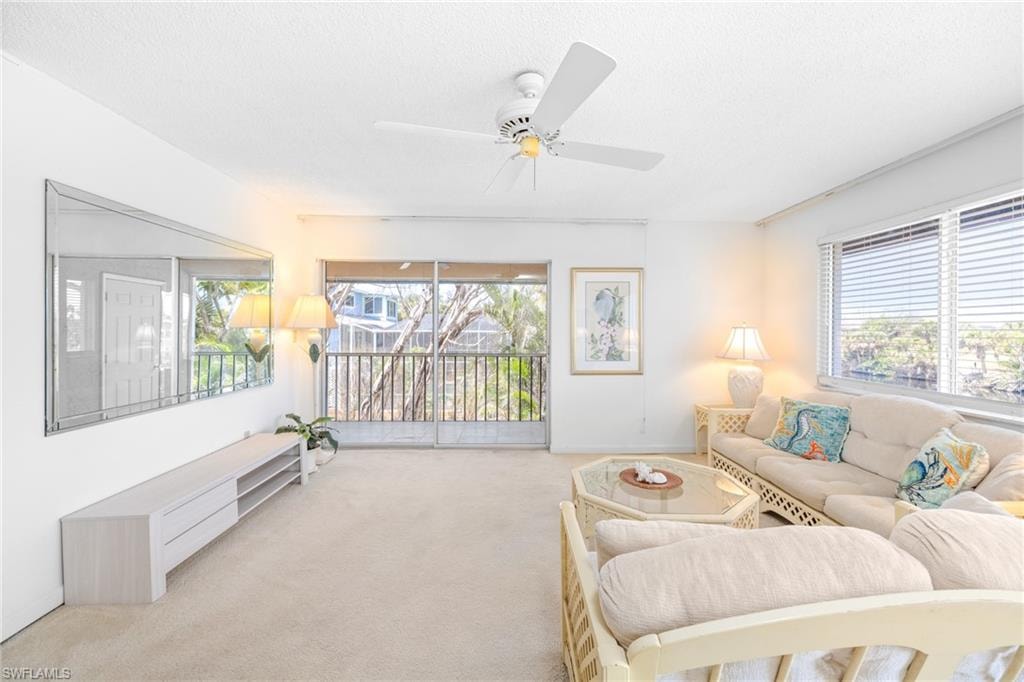 Carpeted living room featuring ceiling fan and a textured ceiling