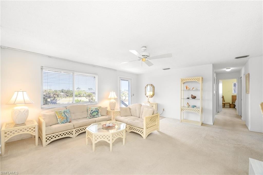 Living area with a ceiling fan, visible vents, and carpet