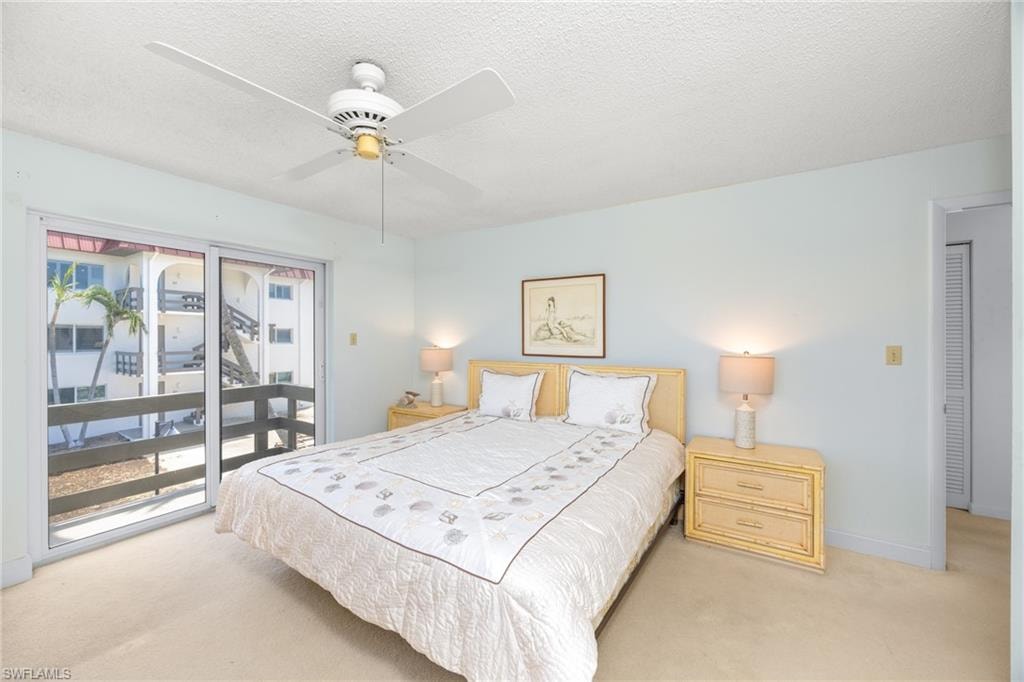 Bedroom with a textured ceiling, access to exterior, baseboards, a ceiling fan, and carpet floors