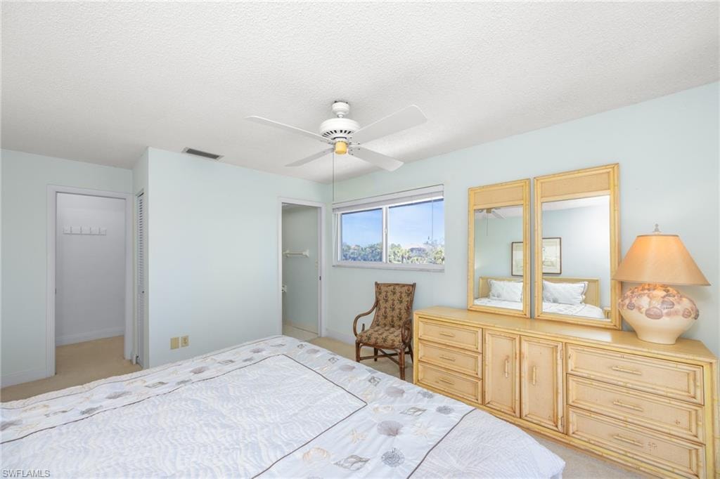 Bedroom featuring ceiling fan, light carpet, a textured ceiling, and visible vents