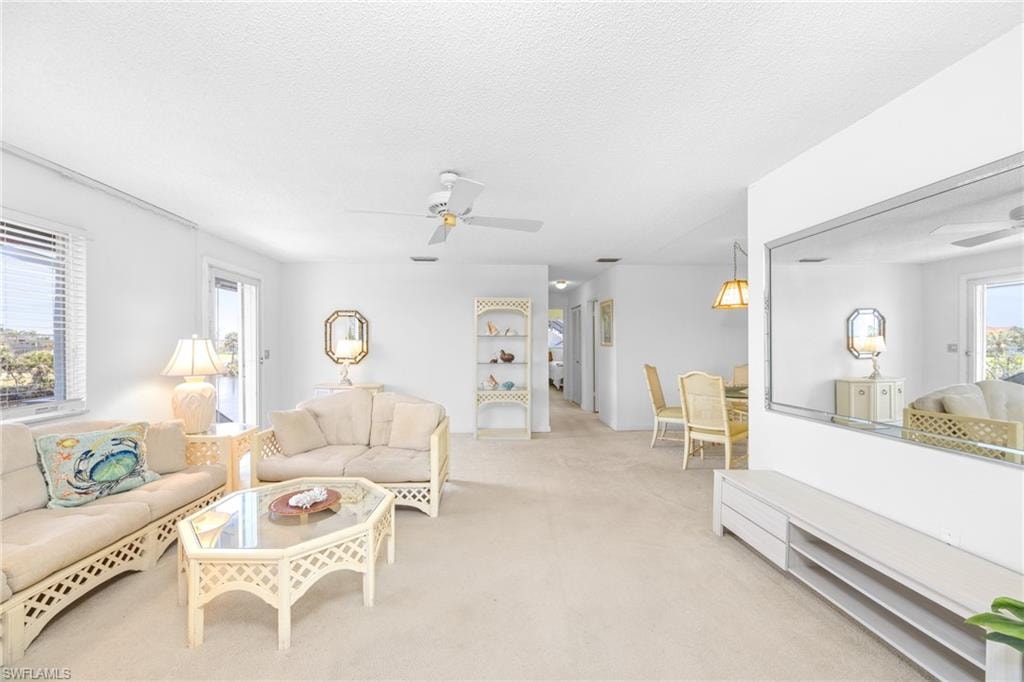 Living area featuring light colored carpet, a textured ceiling, and ceiling fan