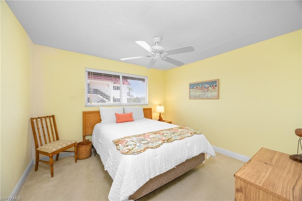 Bedroom featuring ceiling fan, baseboards, and light colored carpet