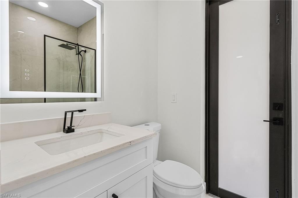 Pool bathroom with vanity, toilet, and a stall shower