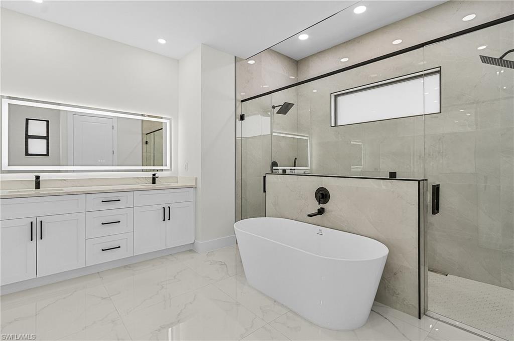 Master bathroom with a stall shower, baseboards, vanity, a freestanding bath, and porcelain floors