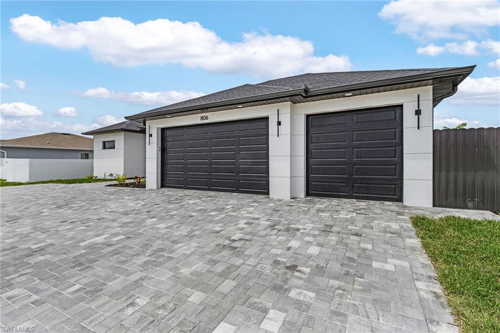 Garage featuring fence and paved driveway