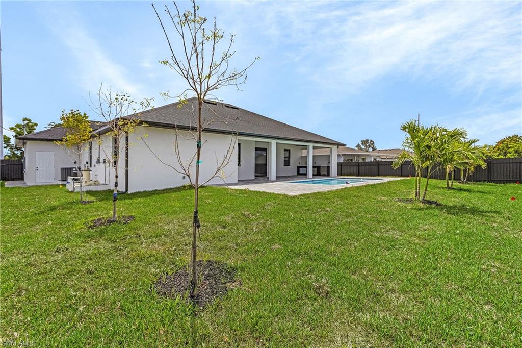 Back of house with a lawn, stucco siding, and a fenced backyard