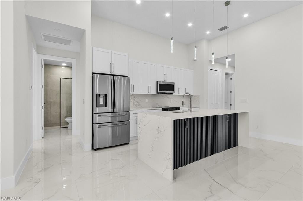 Kitchen with marble finish floor, a sink, white cabinetry, and stainless steel appliances