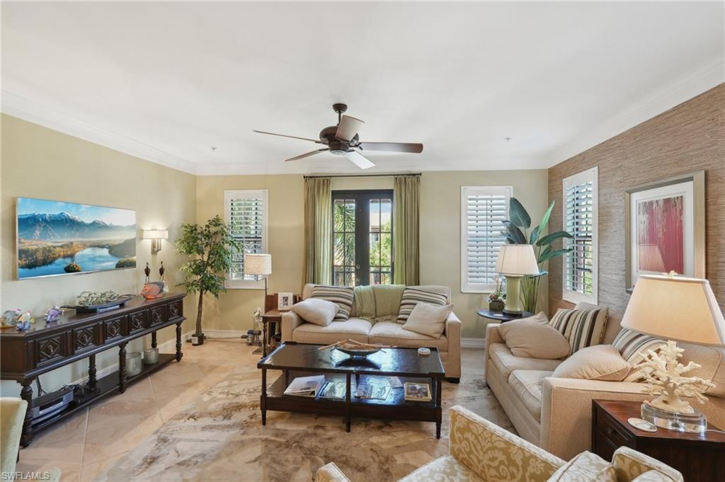 Living area featuring light tile patterned floors, baseboards, crown molding, and a ceiling fan