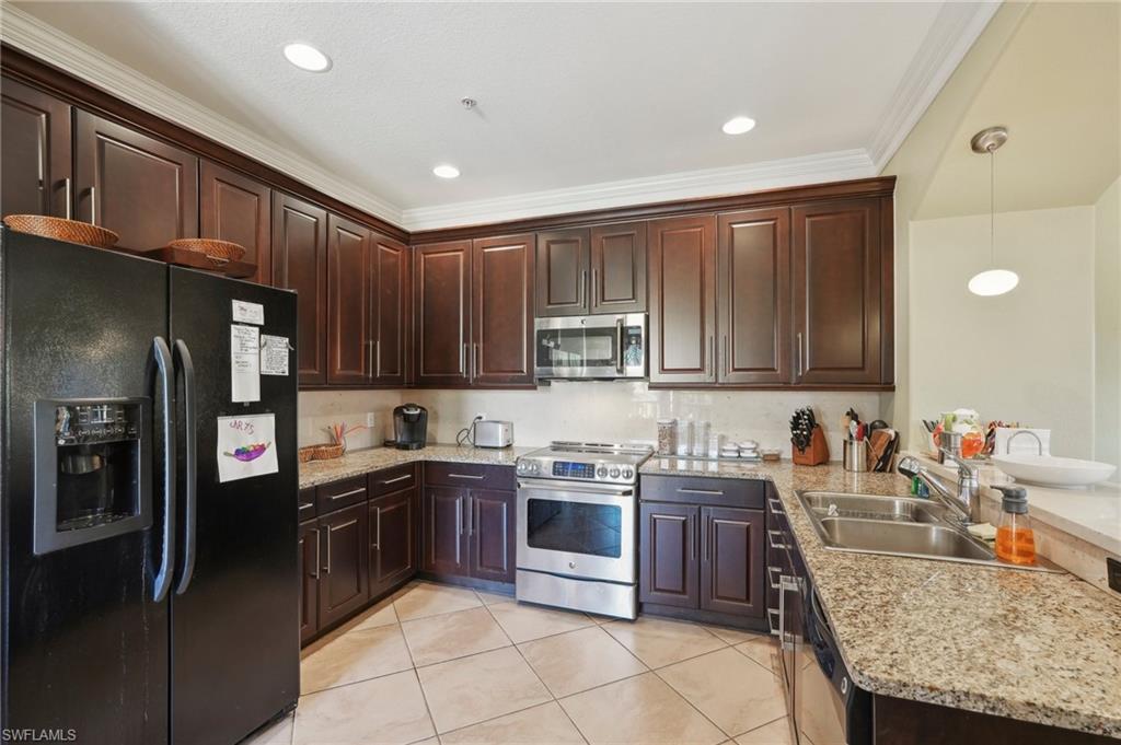 Kitchen with crown molding, a sink, light tile patterned floors, a peninsula, and stainless steel appliances
