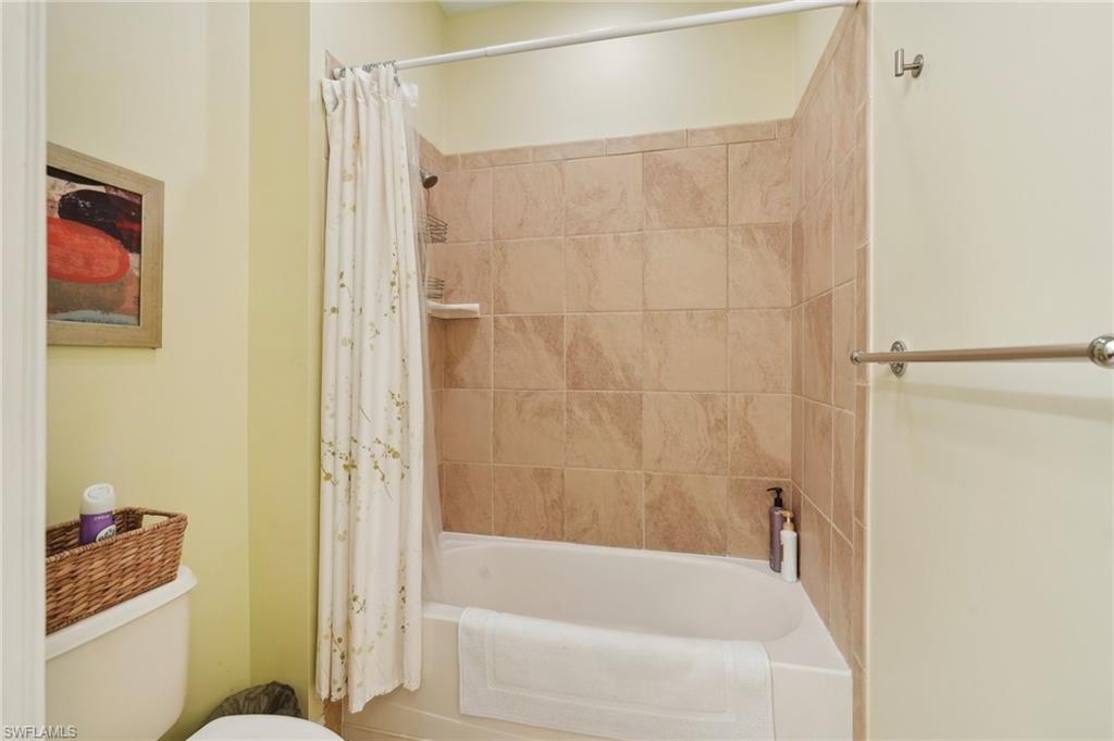 Bathroom with toilet and shower / bathtub combination with curtain