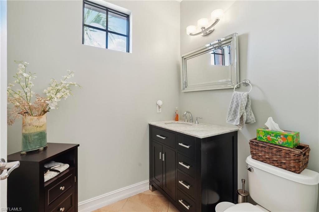 Bathroom featuring vanity, baseboards, tile patterned floors, and toilet