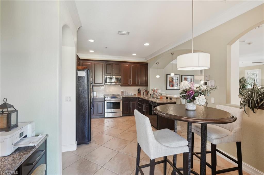 Kitchen featuring dark brown cabinets, light tile patterned flooring, a sink, recessed lighting, and black appliances