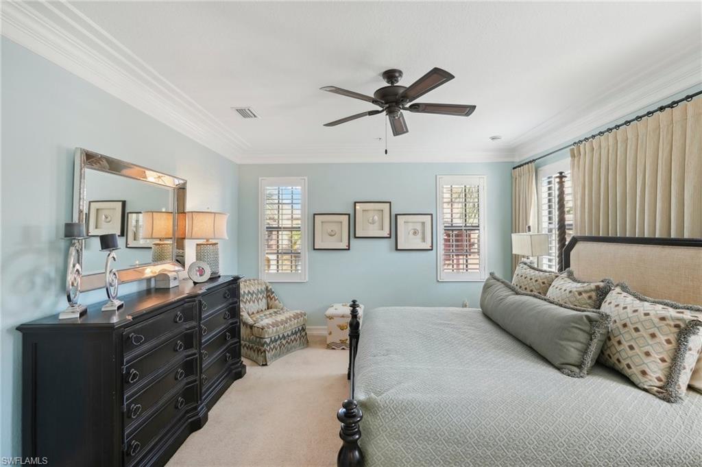 Bedroom featuring ceiling fan, light carpet, baseboards, visible vents, and ornamental molding