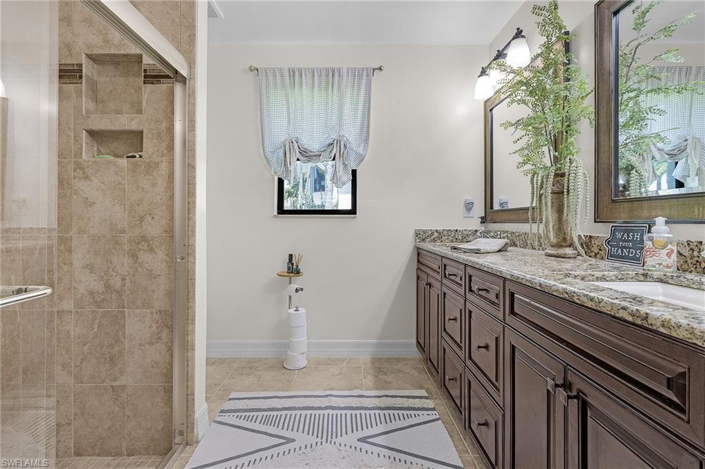 Guest bathroom close proximity to Bedrooms 3 & 4, featuring baseboards, double vanity, and a shower stall overlooking north side yard
