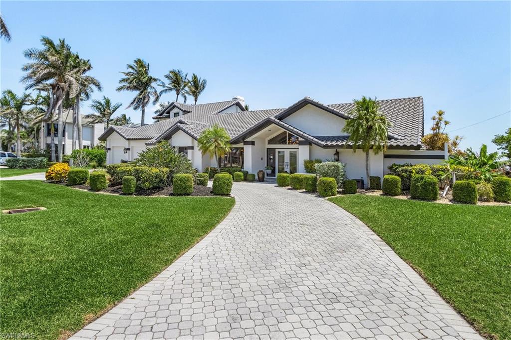 View of front of house with a tile roof, a front lawn, stucco siding, decorative driveway, and french doors