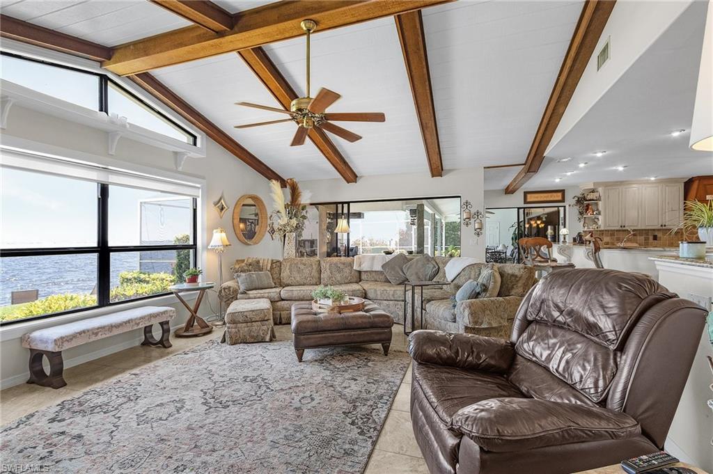 Living area featuring tile patterned floors, a wealth of natural light, and ceiling fan and sliders to the lanai and open to the kitchen and casual dining area
