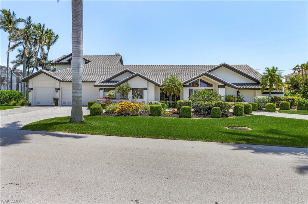 View of front of property featuring a tiled roof, driveway, a front yard, a garage, and stucco siding