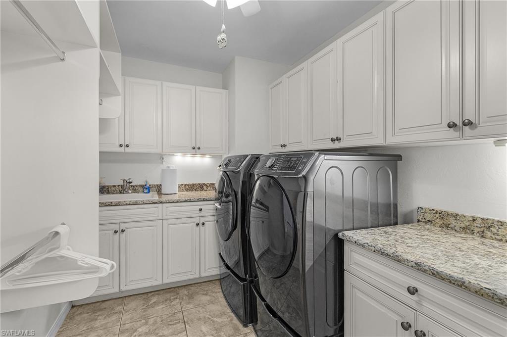 Clothes washing area with washer and clothes dryer, a sink, and cabinet space and granite counters