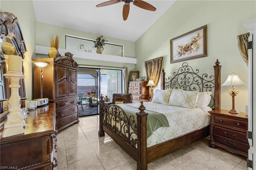 Primary Bedroom downstairs with marble finish floor, ceiling fan, cathedral ceiling, and access to pool area