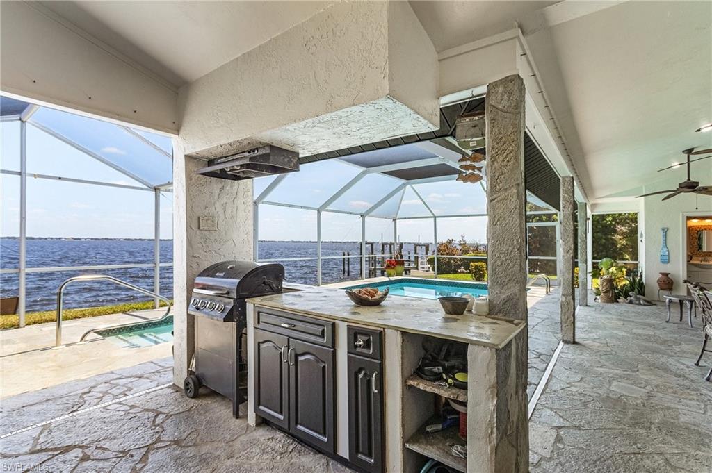 View of patio with a water view, ceiling fans, an outdoor pool, and a large under truss lanai to enjoy year round