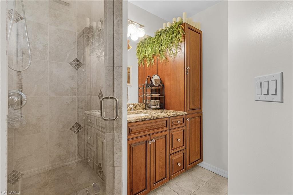 Ensuite Full bath with baseboards, a walk in shower, vanity with granite counter, cabinets and walk in closet