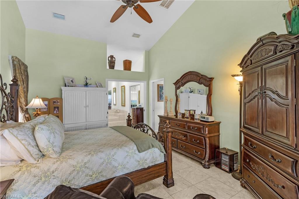 Primary Bedroom downstairs with cathedral ceiling, and light tile patterned floors