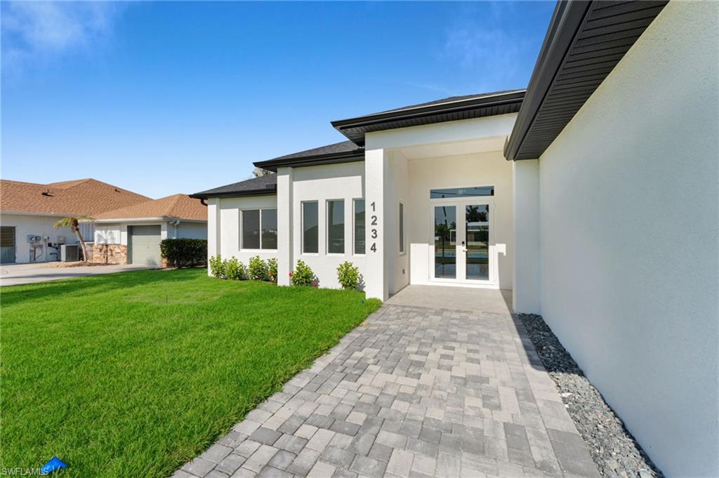 View of front of property with decorative driveway, a garage, a residential view, and a front lawn