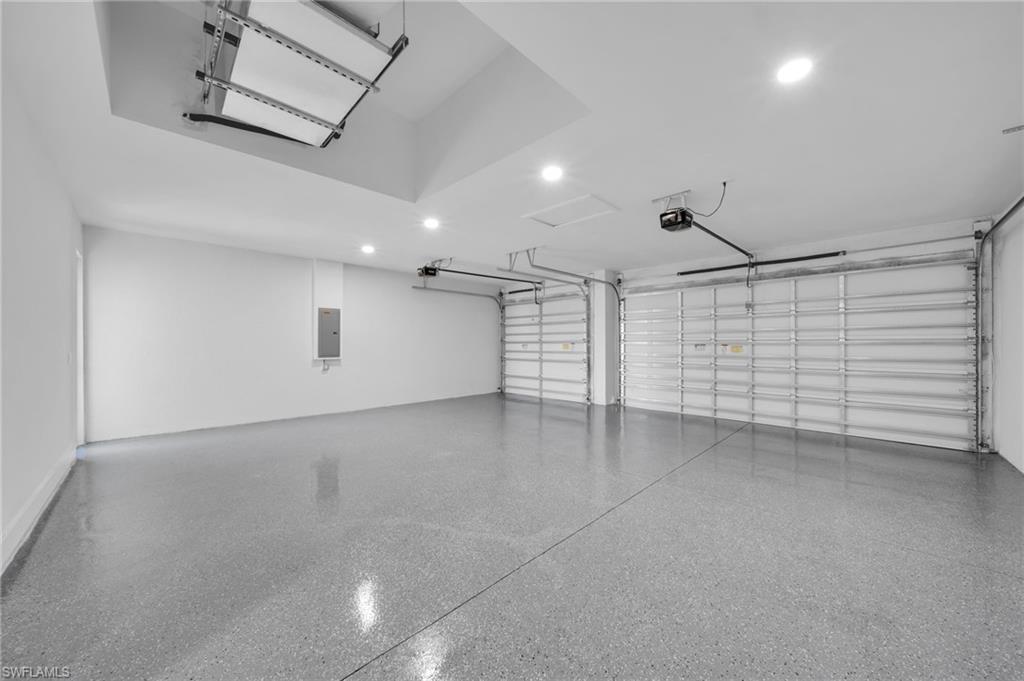 Garage with recessed lighting, a garage door opener, and water heater
