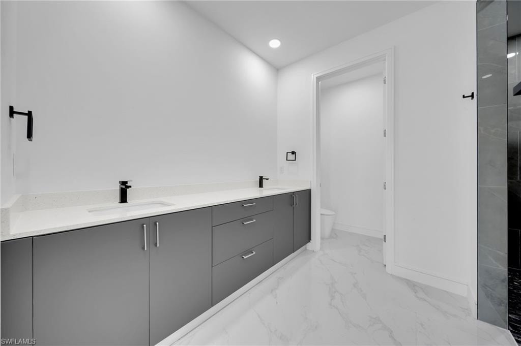 Full bath with toilet, tiled shower, marble finish floor, and vanity