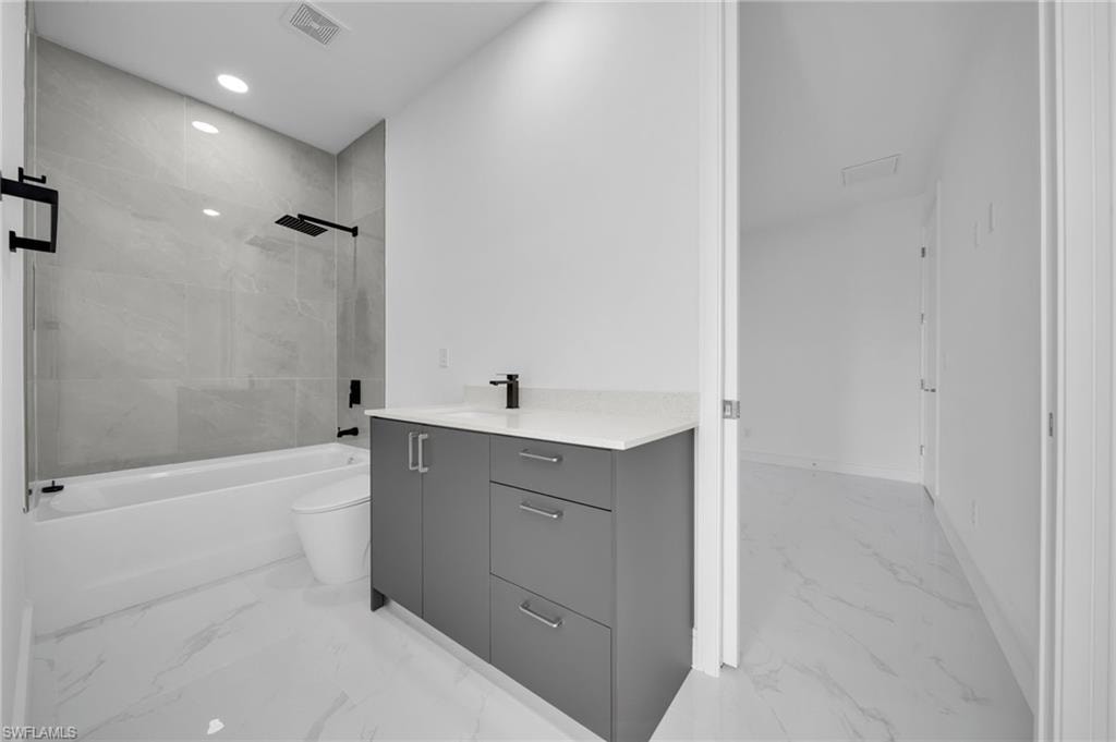 Bathroom with toilet, baseboards, marble finish floor, and vanity