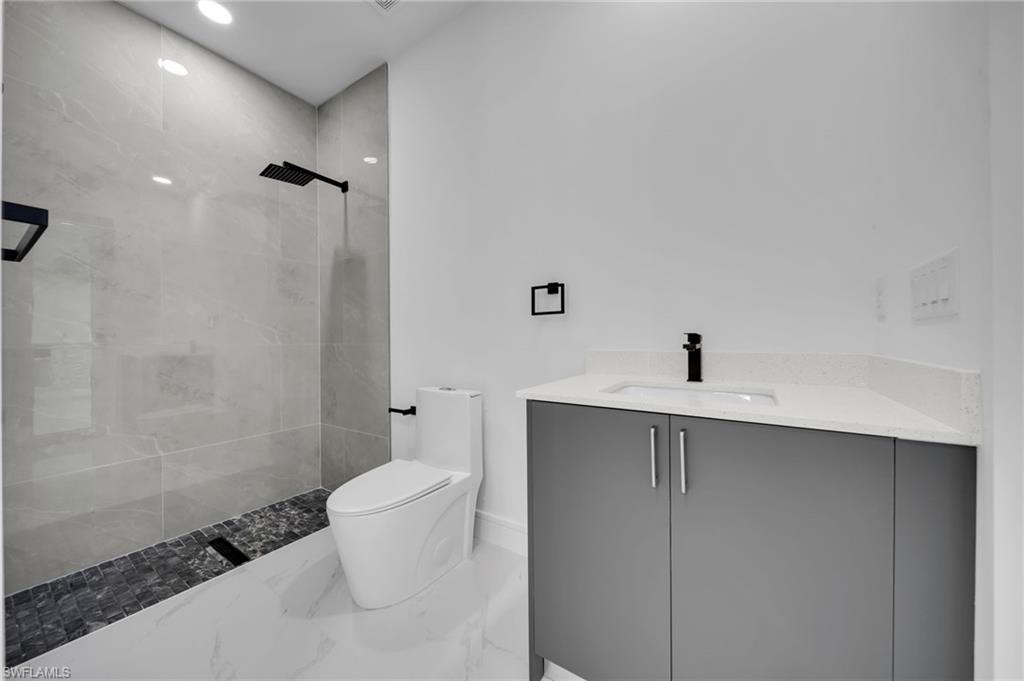 Bathroom with vanity, marble finish floor, toilet, baseboards, and a ceiling fan