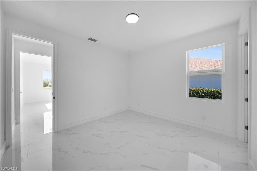 Bathroom with a tile shower, vanity, toilet, marble finish floor, and baseboards