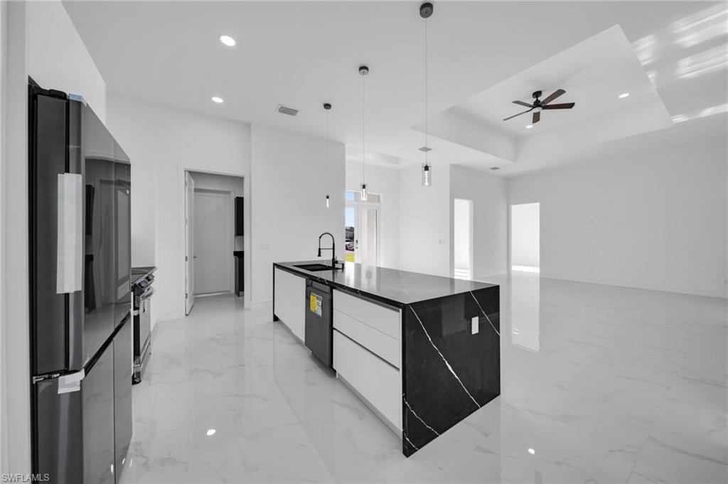 Kitchen featuring marble finish floor, modern cabinets, white cabinets, a sink, and appliances with stainless steel finishes