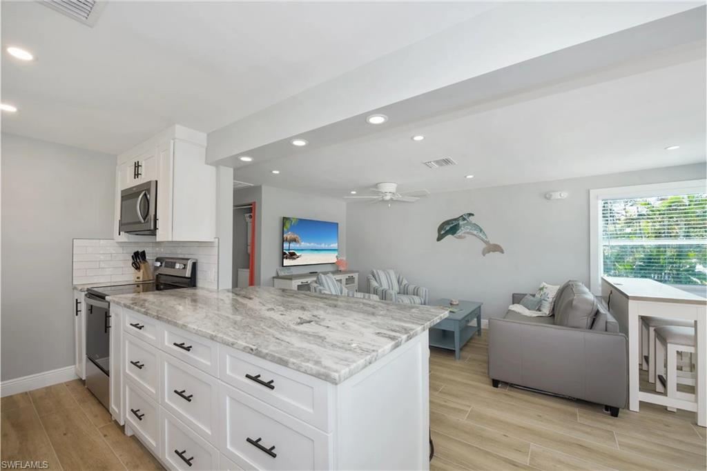 Gourmet kitchen with stainless steel appliances, granite countertops, and a spacious island  (Beach home 1) - Virtually Edited Image