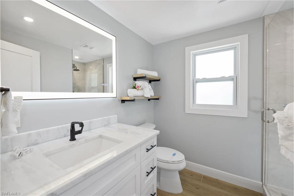 Modern bathroom featuring a sleek vanity, updated fixtures, and a glass-enclosed shower (Beach home 1) - Virtually Edited Image