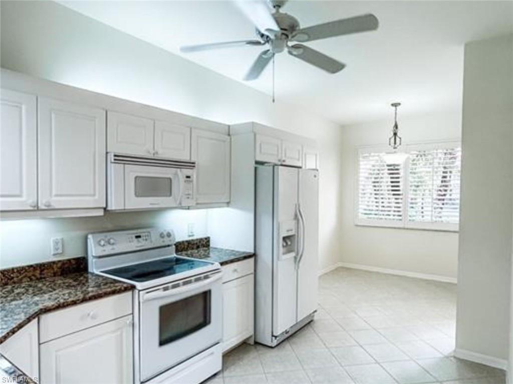 Kitchen with white appliances, a ceiling fan, baseboards, decorative light fixtures, and light tile patterned floors